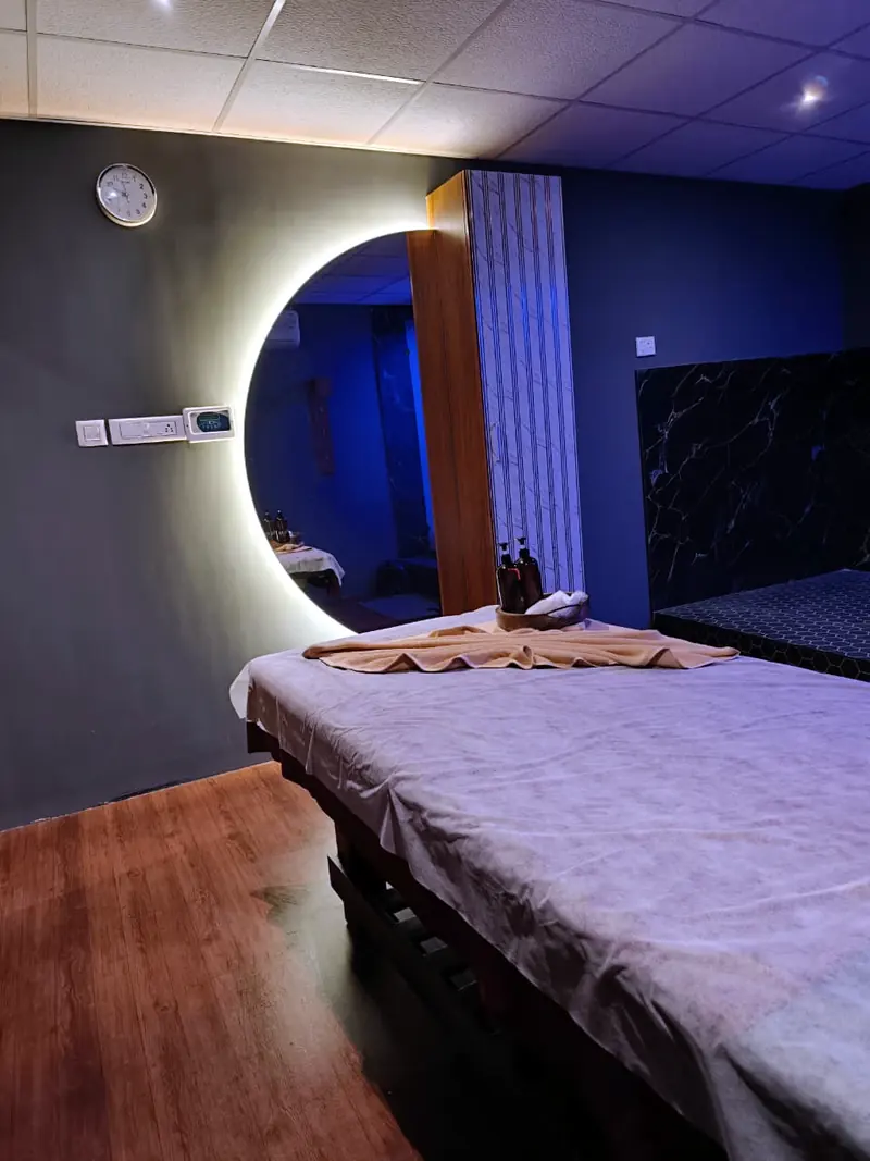 Aura private treatment room with a massage bed and round mirror