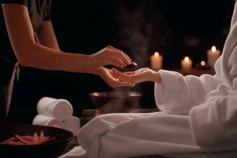 Therapist placing a warm basalt stone into a guest's palm